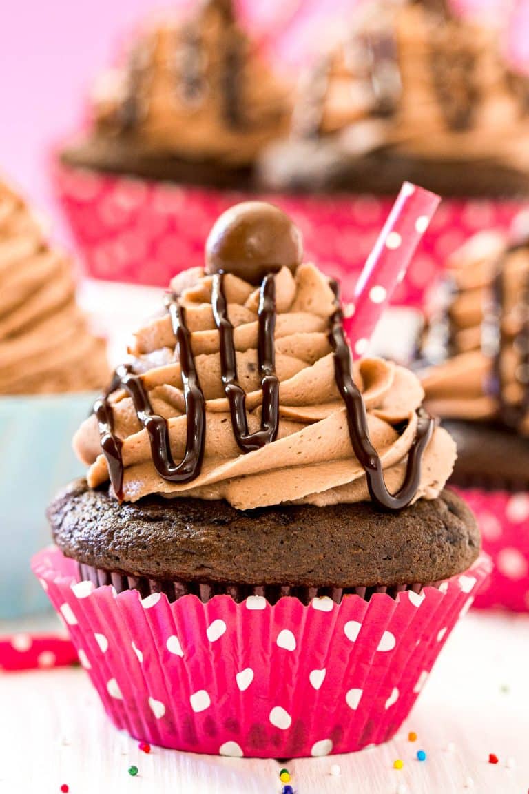 Close up photo of a chocolate milkshake cupcake with more cupcakes behind it.