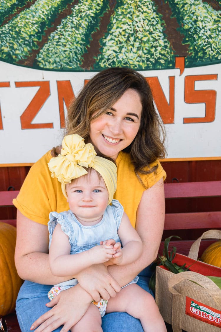 Mother an infant daughter sitting on a bench at a farm stand.