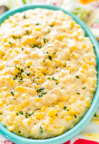 Close up photo of a teal serving dish filled with cheesy corn.