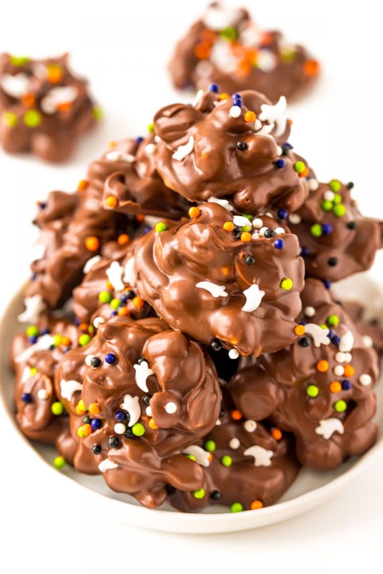 A plate filled with crockpot candy decorated with halloween sprinkles.