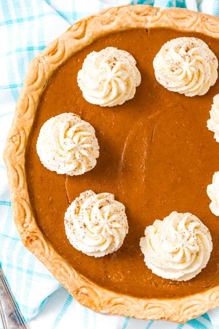 Overhead photo of a pumpkin pie topped with dollops of whipped cream.