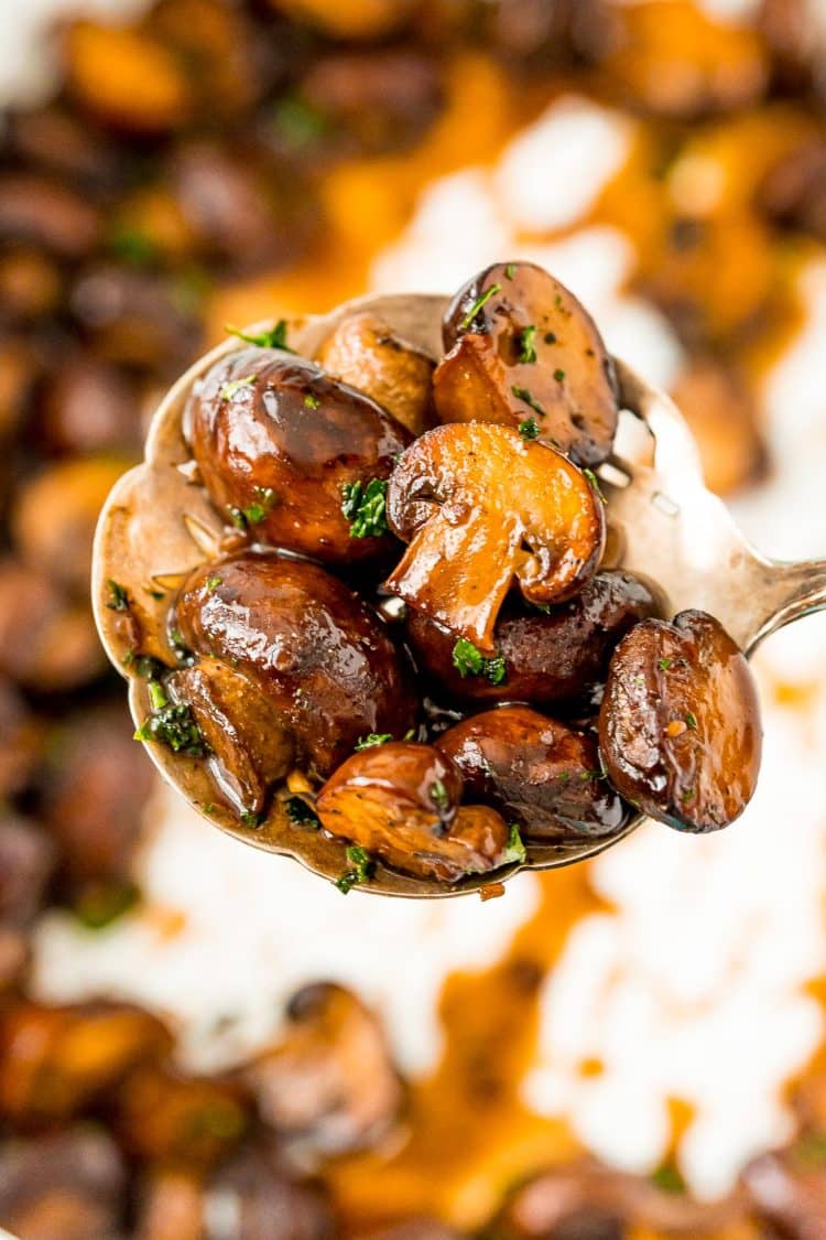 Serving spoon filled with sauteed mushrooms.