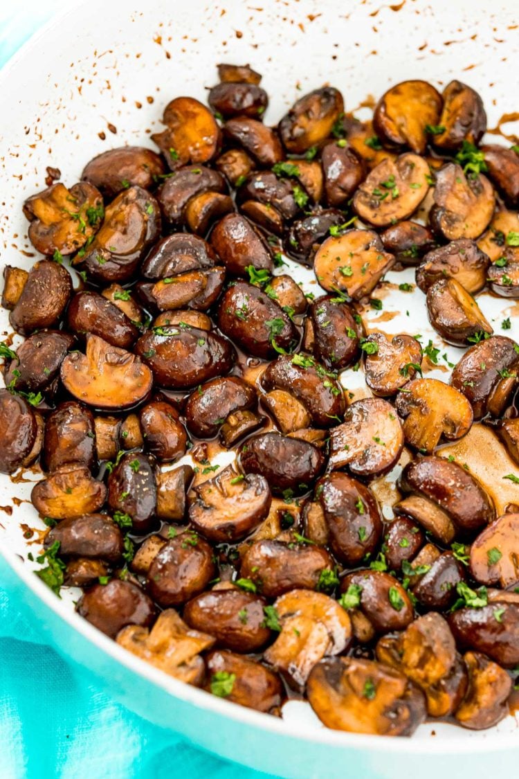 Sauteed mushrooms garnished with parsley in a skillet.