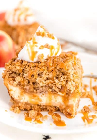 Square slice of apple cheesecake bar with caramel drizzle on a white plate.