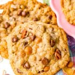 Two cowboy cookies sitting next to a pink plate.