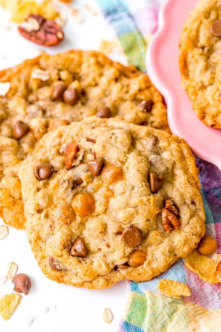 Two cowboy cookies sitting next to a pink plate.