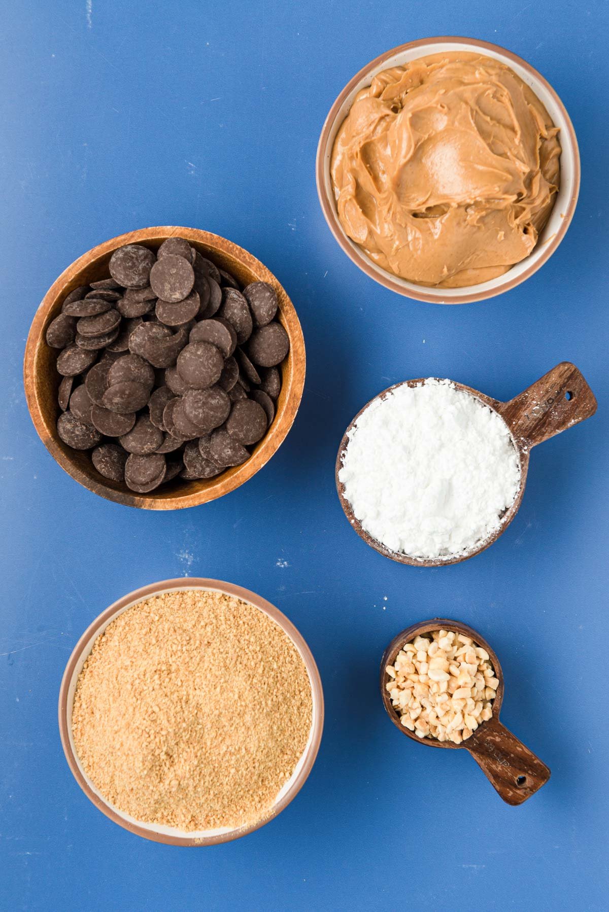Overhead photo of ingredients to make peanut butter balls on a blue surface.