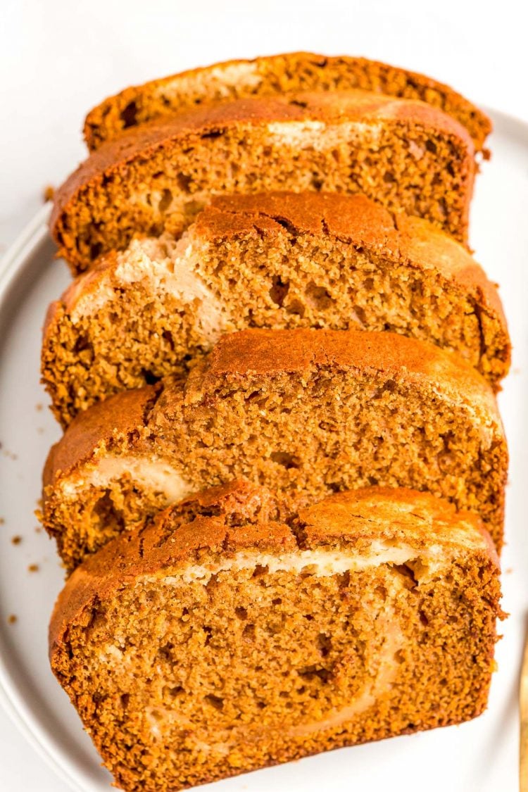 Slices of pumpkin cream cheese bread on a white plate.