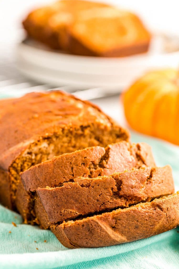 A loaf of pumpkin cream cheese bread on a blue napkin, some of it has been sliced.