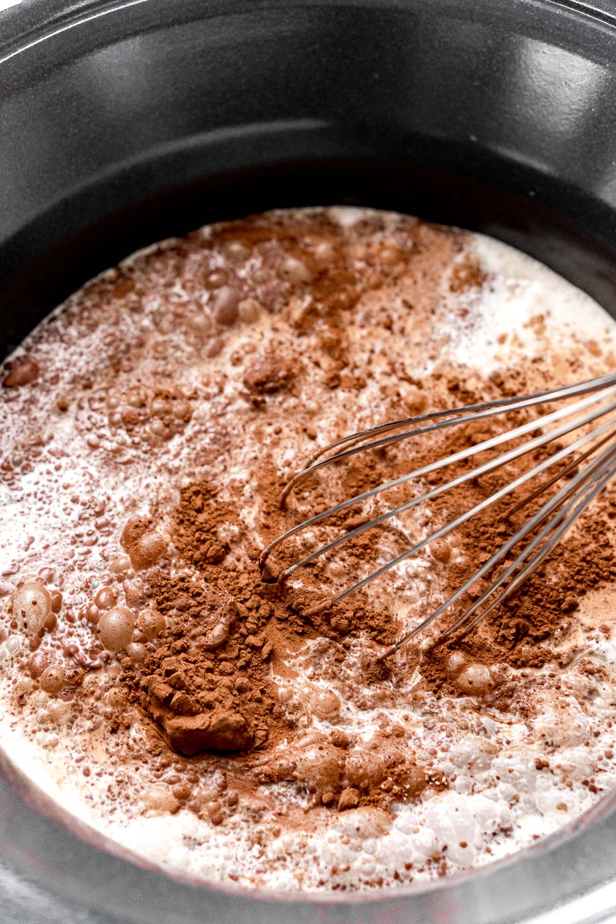 Hot chocolate ingredients being whisked together in a crockpot.
