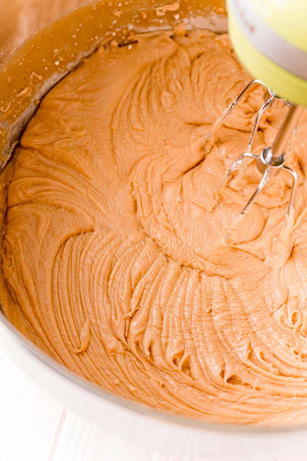 Peanut butter fudge being mixed in a large mixing bowl with a hand mixer.