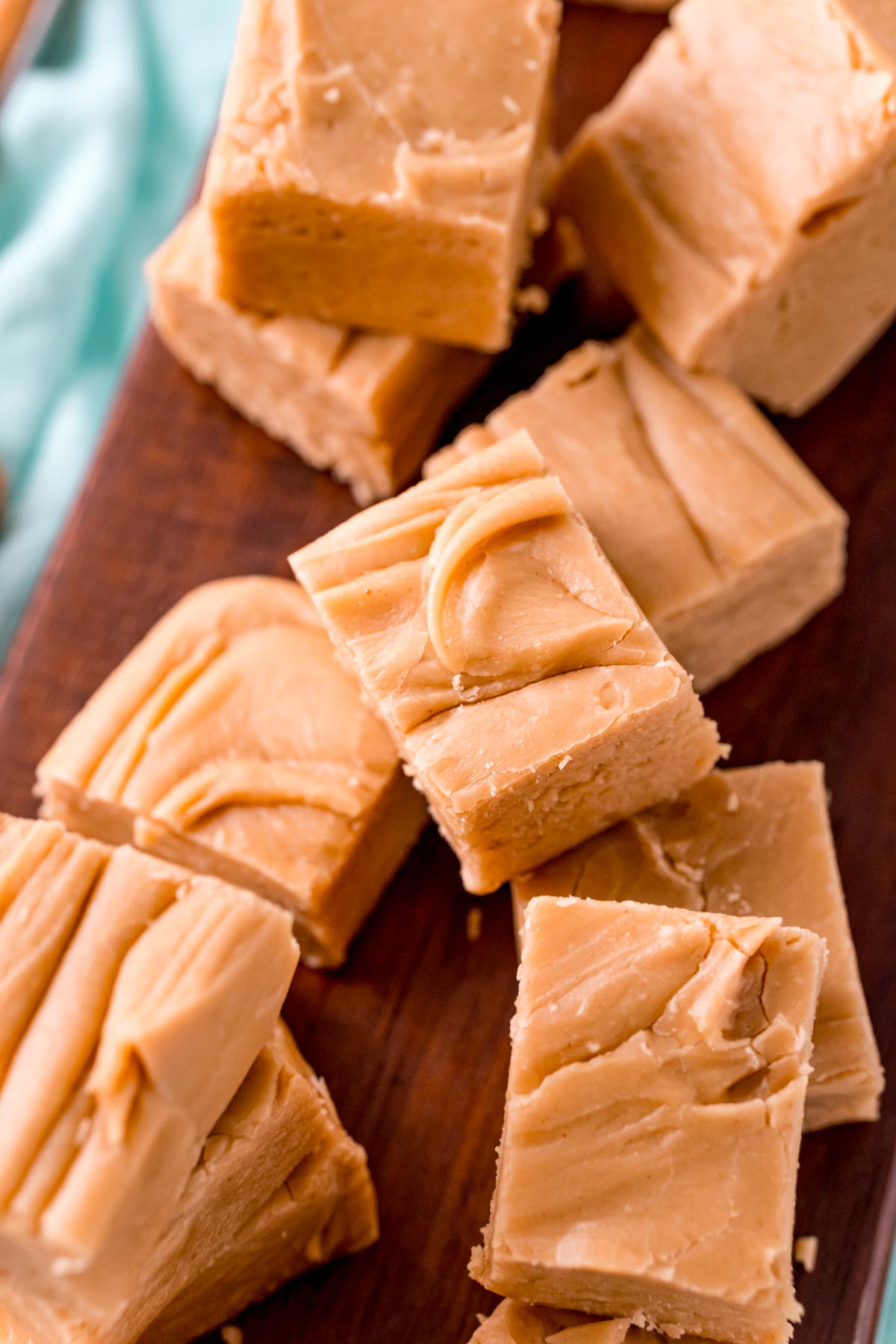 Peanut butter fudge pieces on a dark wood cutting board.