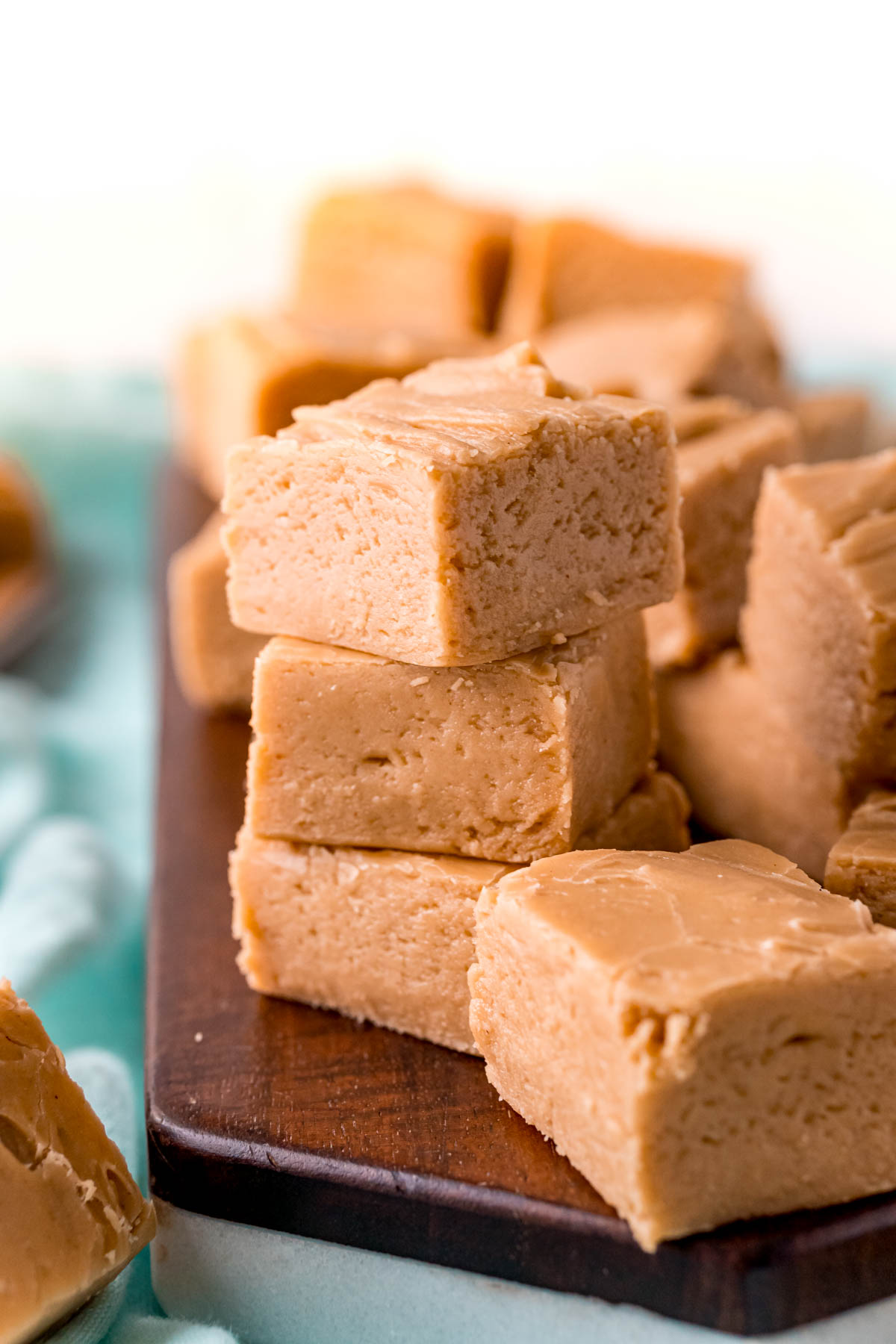 Close up photo of three pieces of peanut butter fudge stacked on top of each other with other pieces around it.