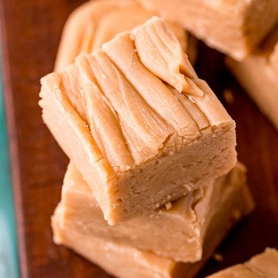 Close up photo of peanut butter fudge stacked on a wooden board.