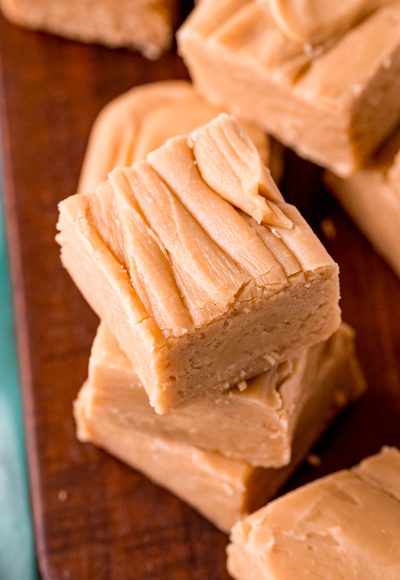 Close up photo of peanut butter fudge stacked on a wooden board.
