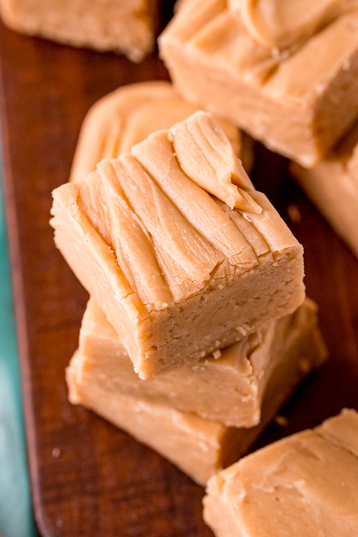 Close up photo of peanut butter fudge stacked on a wooden board.