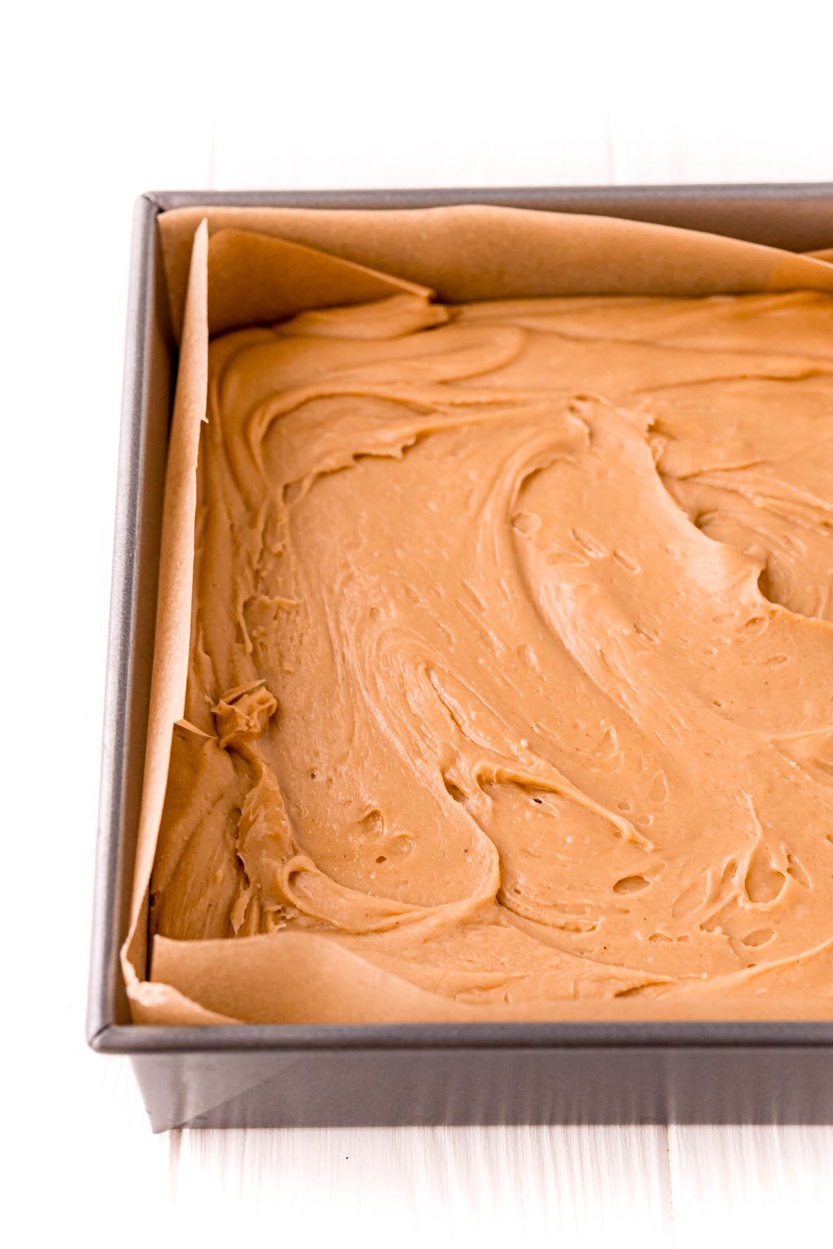 Peanut butter fudge in a baking dish lined with parchment paper.