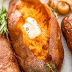 Close up photo of a baked sweet potato with garnishes around it.