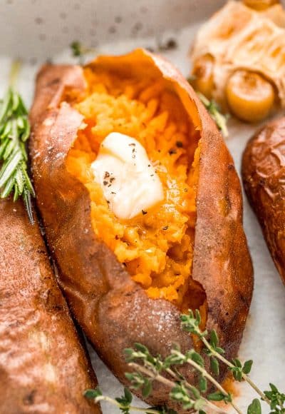 Close up photo of a baked sweet potato with garnishes around it.