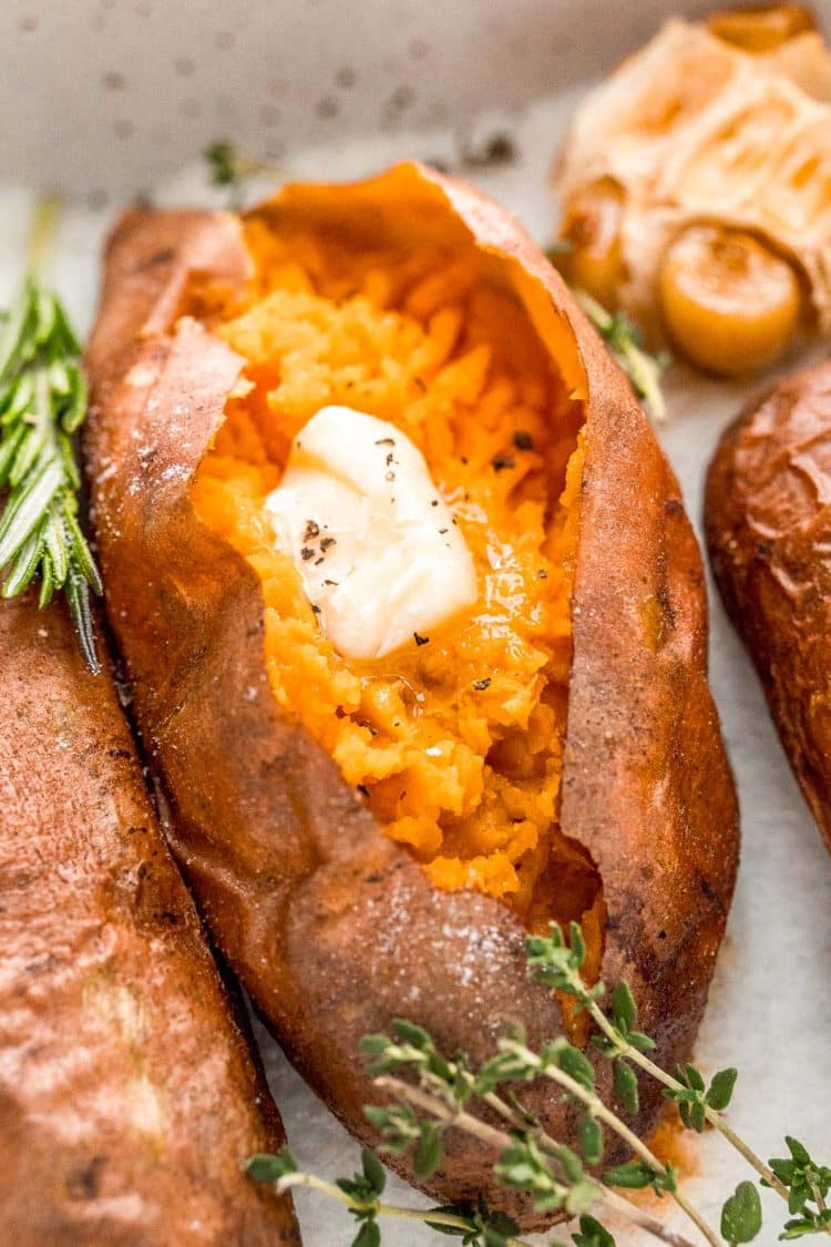 Close up photo of a baked sweet potato with garnishes around it.