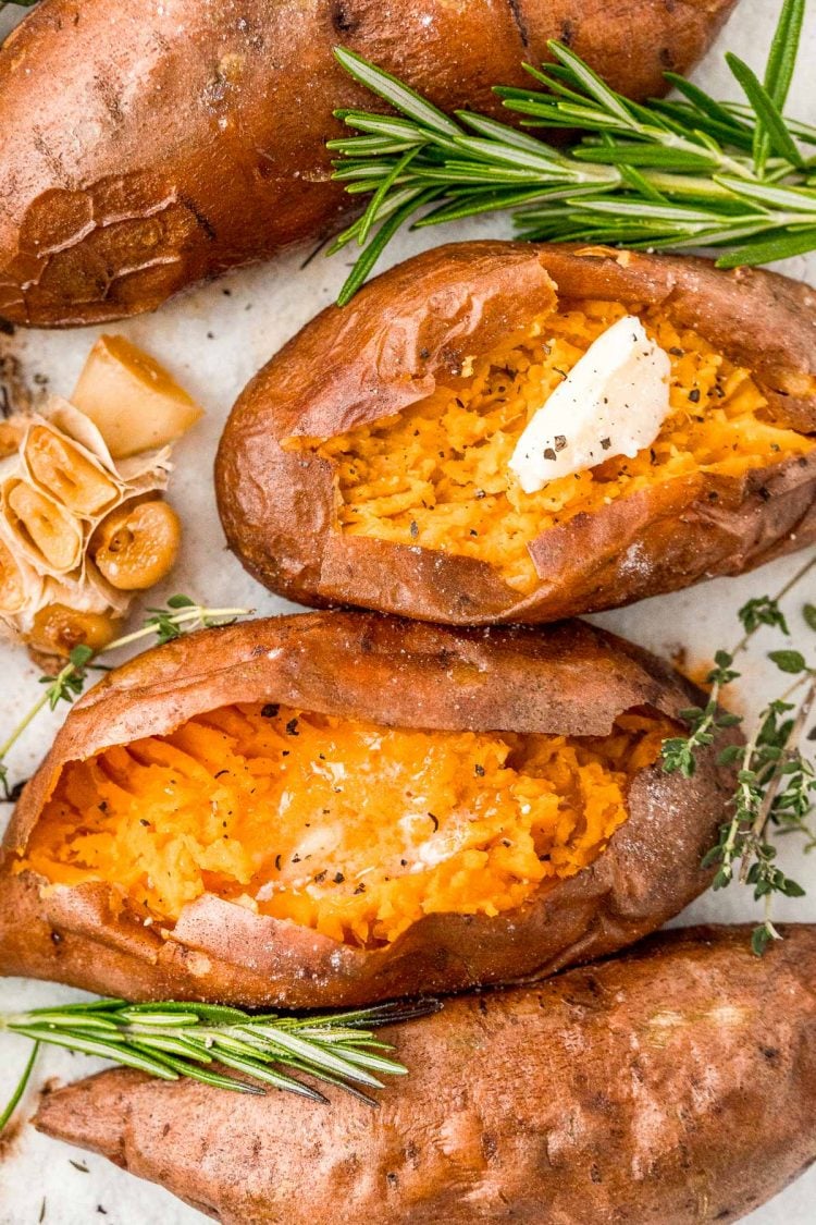 Overhead photos of baked sweet potatoes, the middle ones have been sliced into and topped with butter, salt, and pepper.