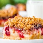 Close up photo of a slice of cranberry cheesecake bars on a small white plate.