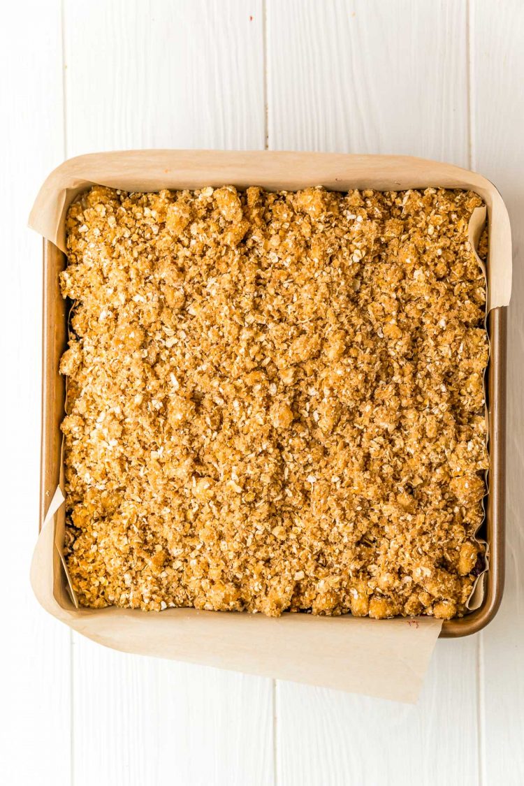 Oatmeal crumble topping on top of a cheesecake in a square baking dish.