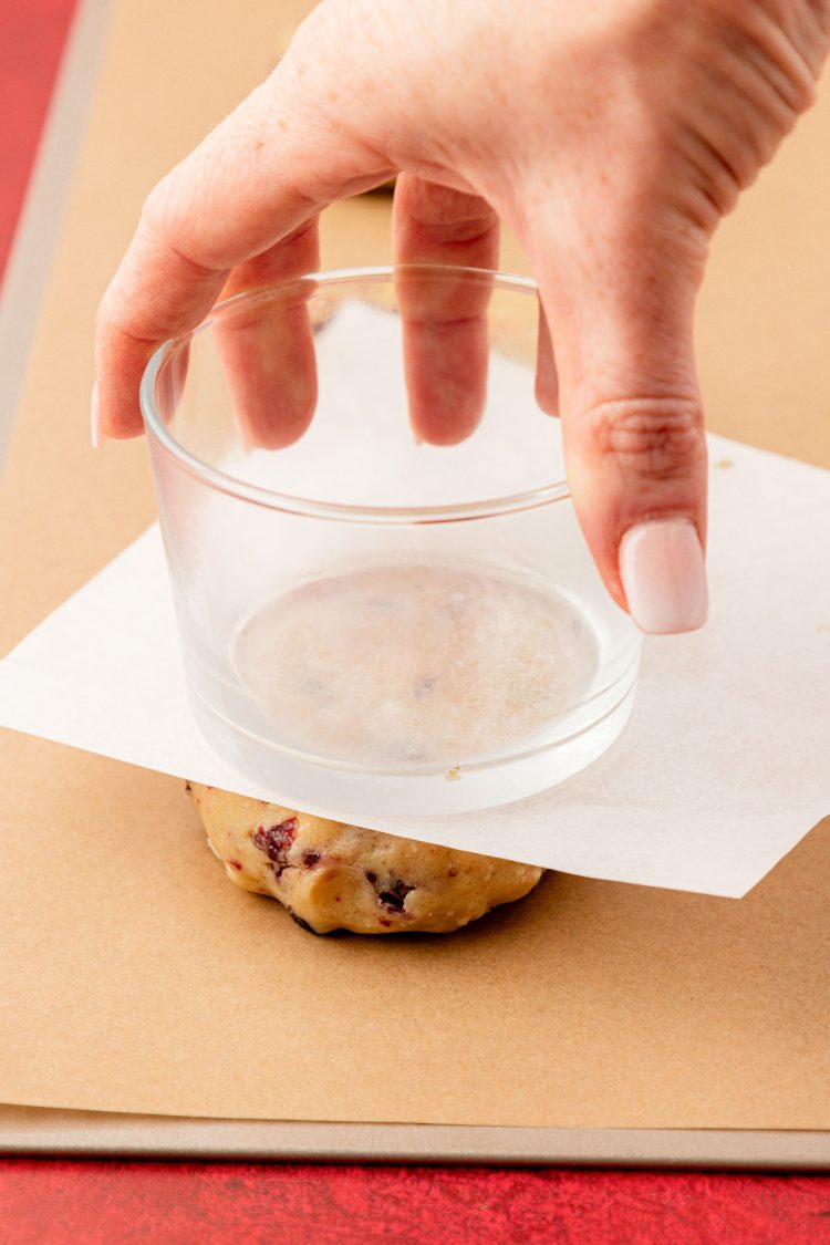 A glass pressing a ball of cookie dough flat.