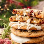 A stack of white chocolate cranberry cookies on a table with the top one split in half.
