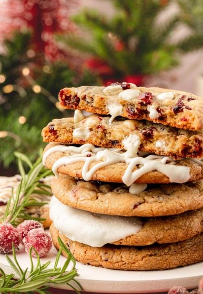 A stack of white chocolate cranberry cookies on a table with the top one split in half.