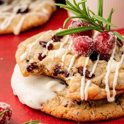 Close up of two cranberry white chocolate chip cookies stacked on top of each other, the top one missing a bite.