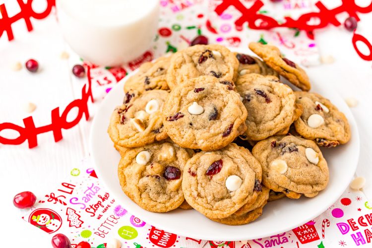 White Chocolate Cranberry Cookies on a white plate with a glass of milk next to it.
