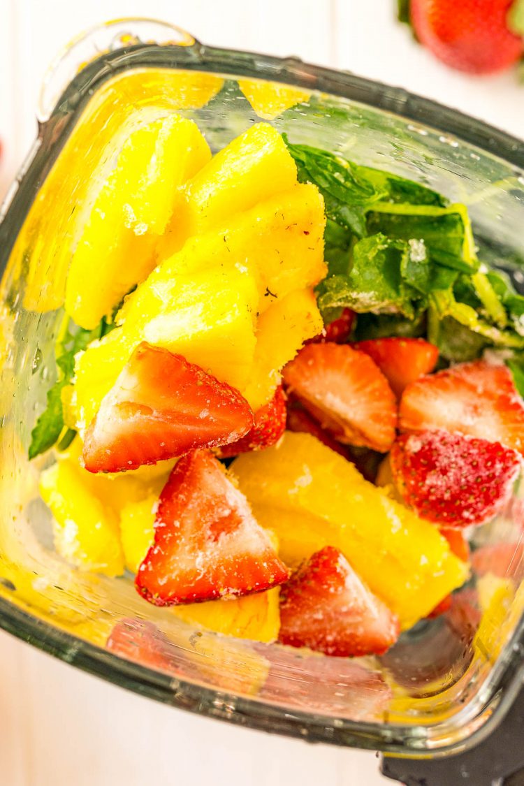 Overhead photo looking into a blender filled with frozen fruits and vegetables.