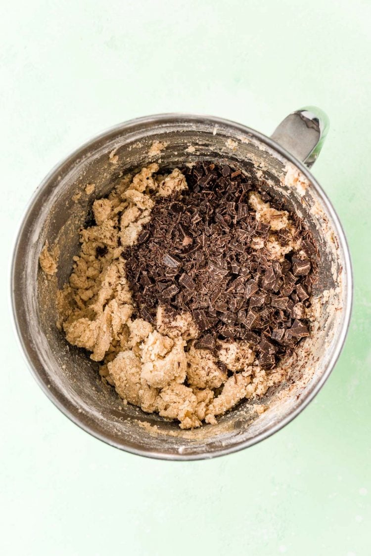 Overhead photo of a mixing bowl filled with cookie dough and chocolate chunks ready to be mixed in.