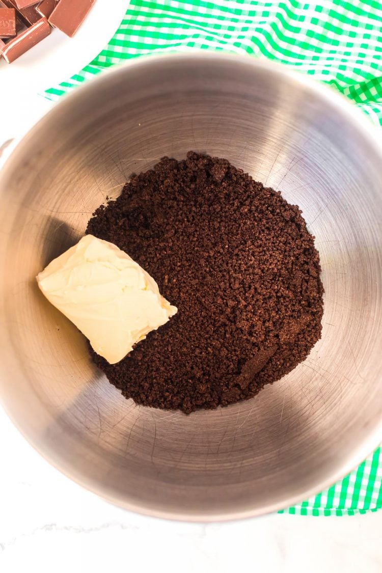 Chocolate cookie crumbs and cream cheese in a stand mixer bowl.