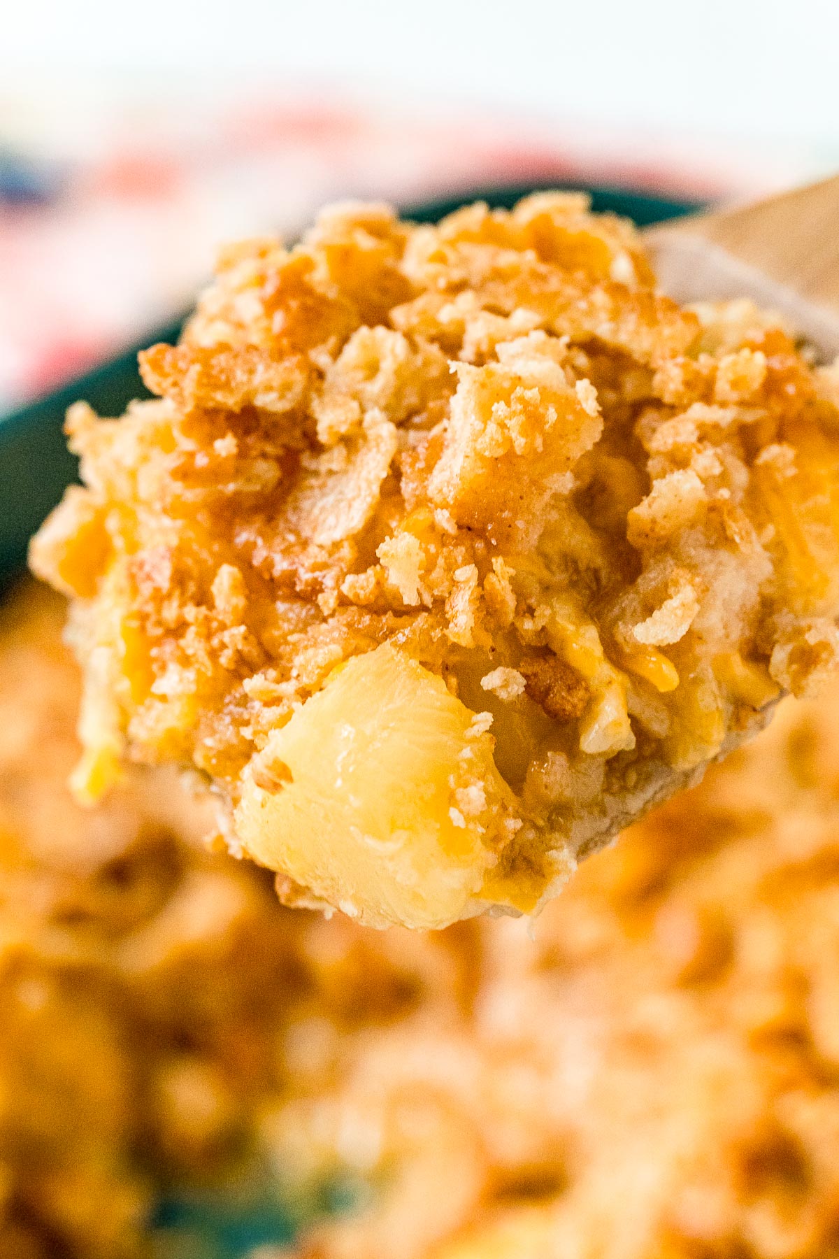 Close up photo of pineapple casserole scooped on a wooden spoon.