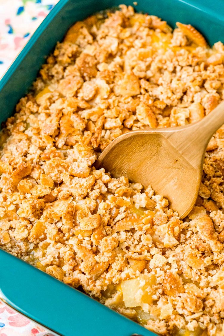 A wooden spoon scooping into a casserole.