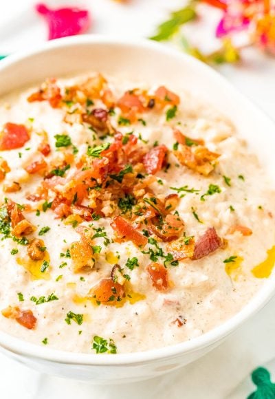 Close up photo of a bowl of chowder topped with bacon and herbs