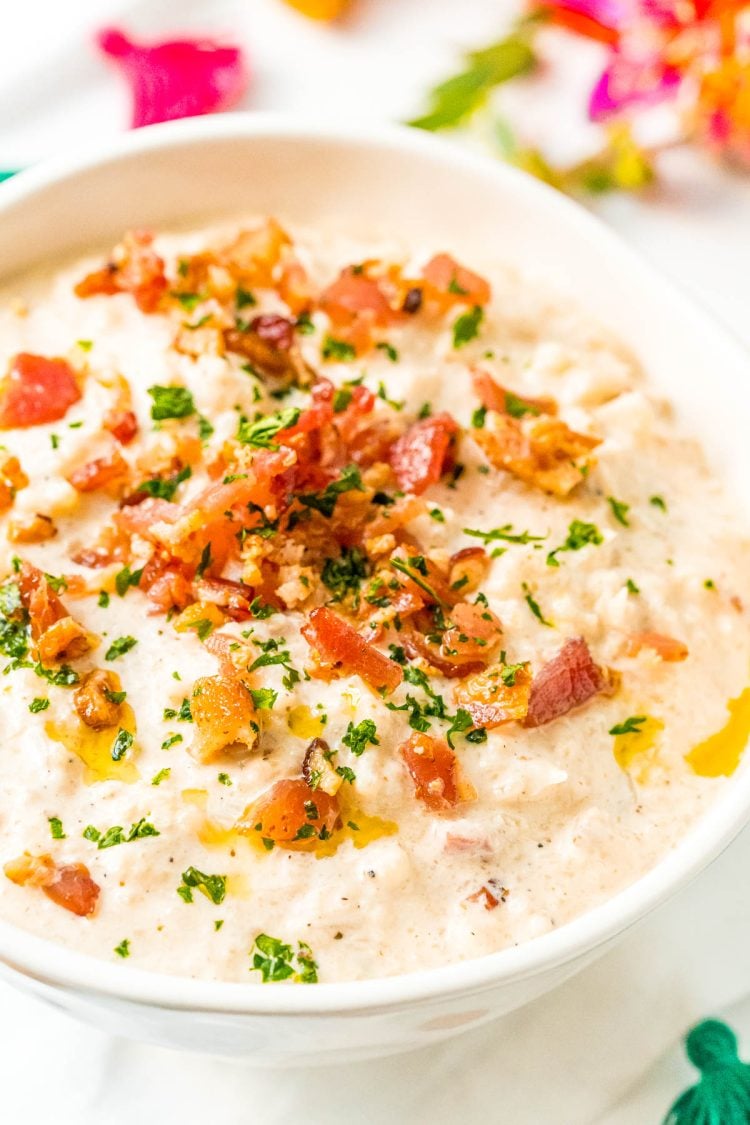 Close up photo of a bowl of chowder topped with bacon and herbs