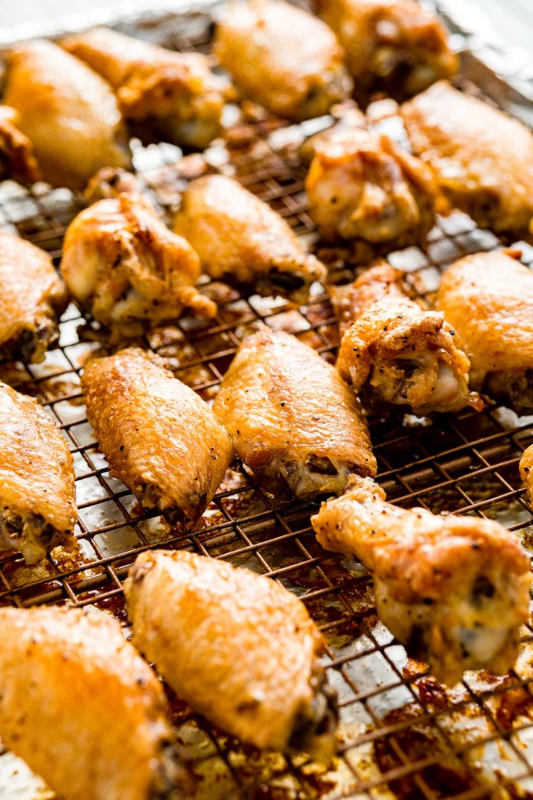 baked chicken wings on a wire rack on a baking sheet just out of the oven.