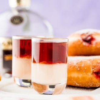 Close up photo of jelly donut shots on the table with jelly donuts in the background.