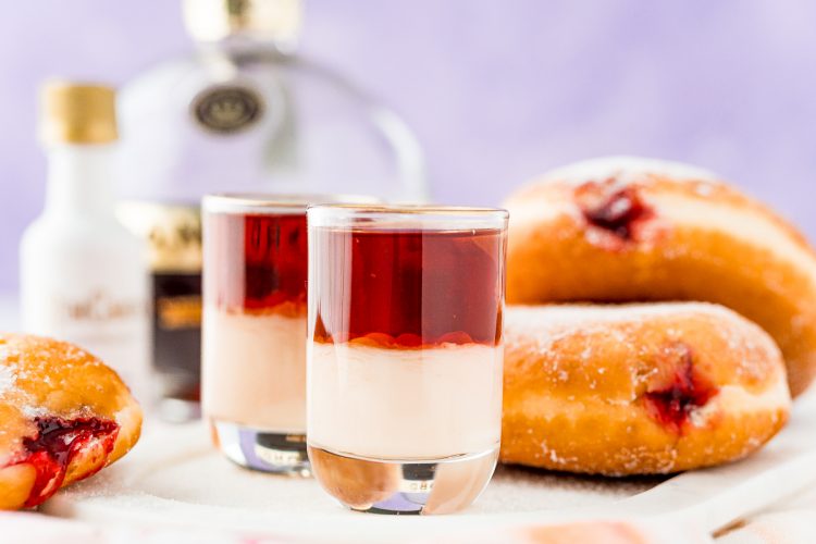 Close up photo of jelly donut shots on the table with jelly donuts in the background.