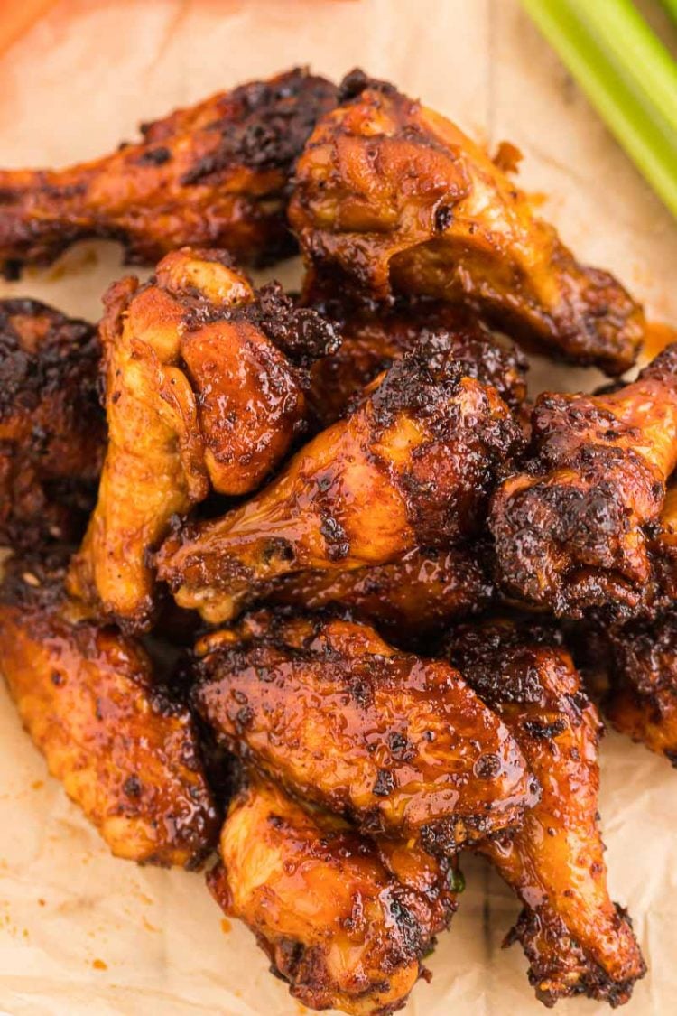 Chicken wings on a piece of parchment paper covered in a sticky hot sauce.