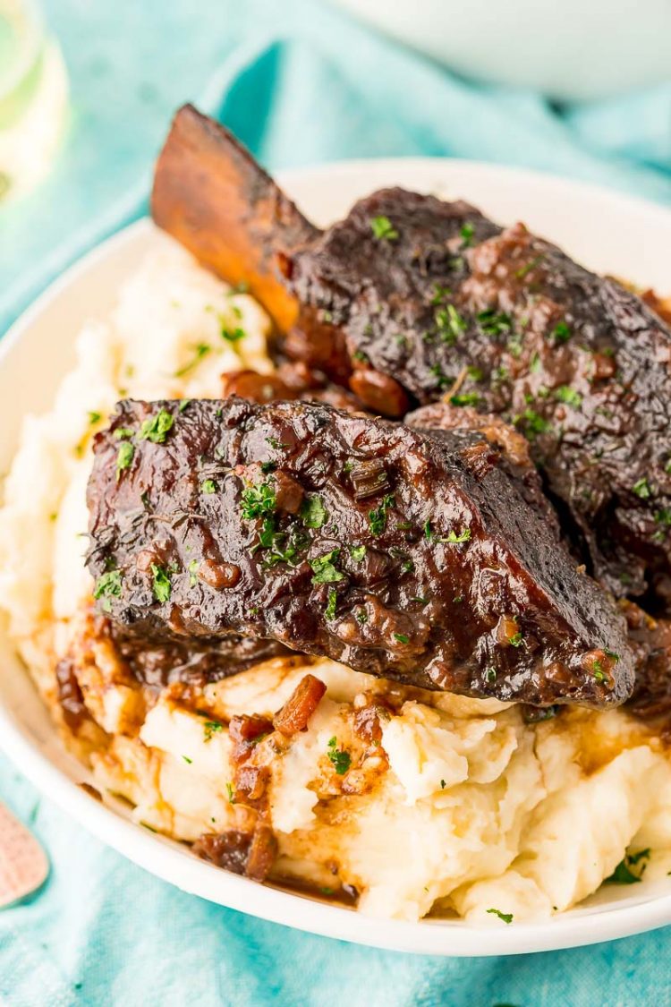 Braised beef short ribs served over a bowl of mashed potatoes.