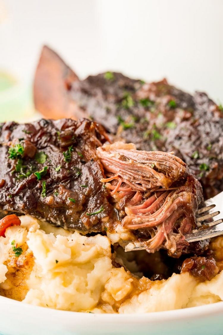 A fork taking a bite out of a beef short rib.