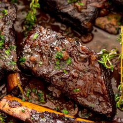 Braised beef short ribs in a pan with sauce.