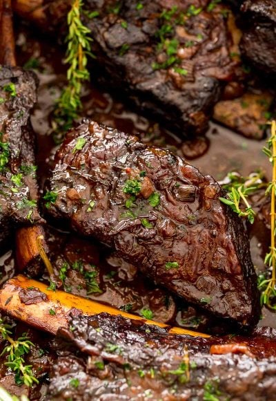 Braised beef short ribs in a pan with sauce.