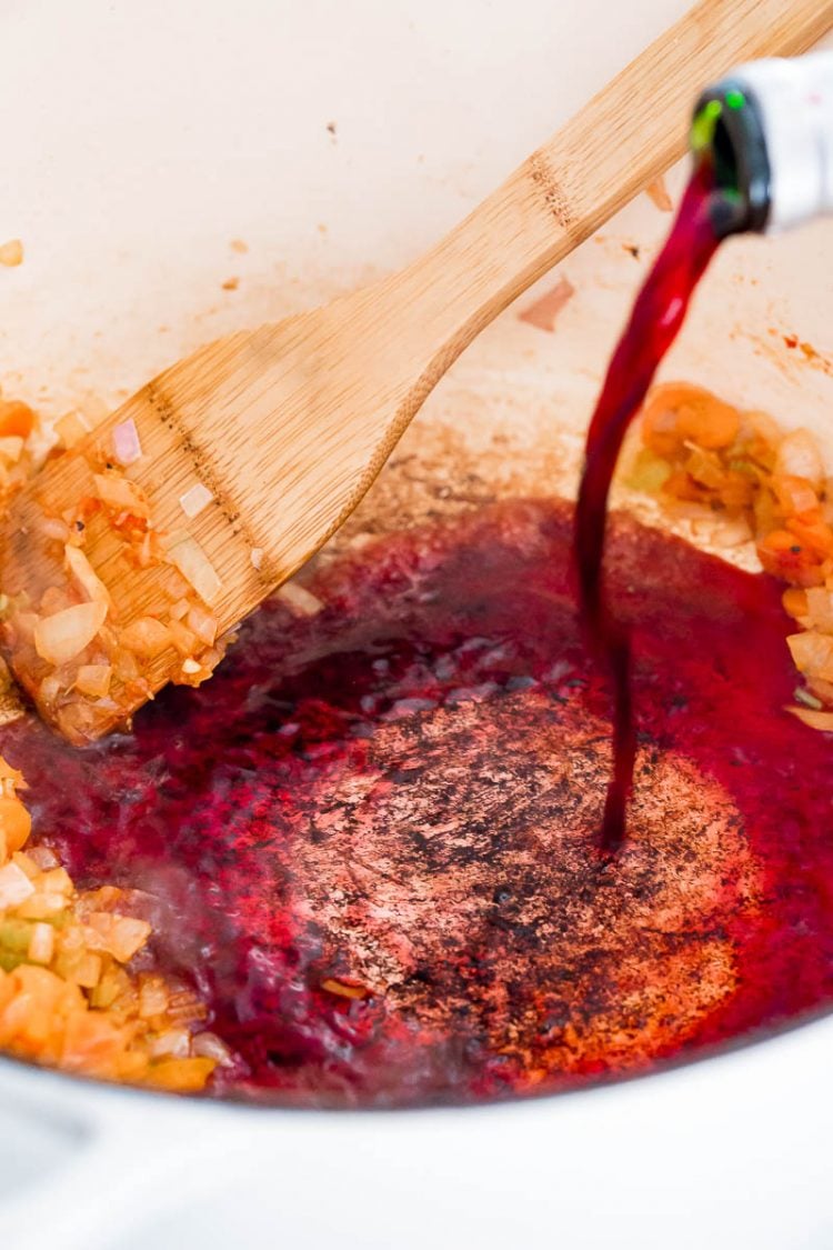 Red wine deglazing the bottom of a dutch oven.