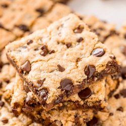 A stack of chocolate chip pan cookies on top of the rest of the pan of cookies.