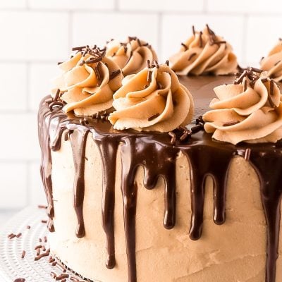 Close up photo of a layer cake with chocolate ganache dripping over the edge.